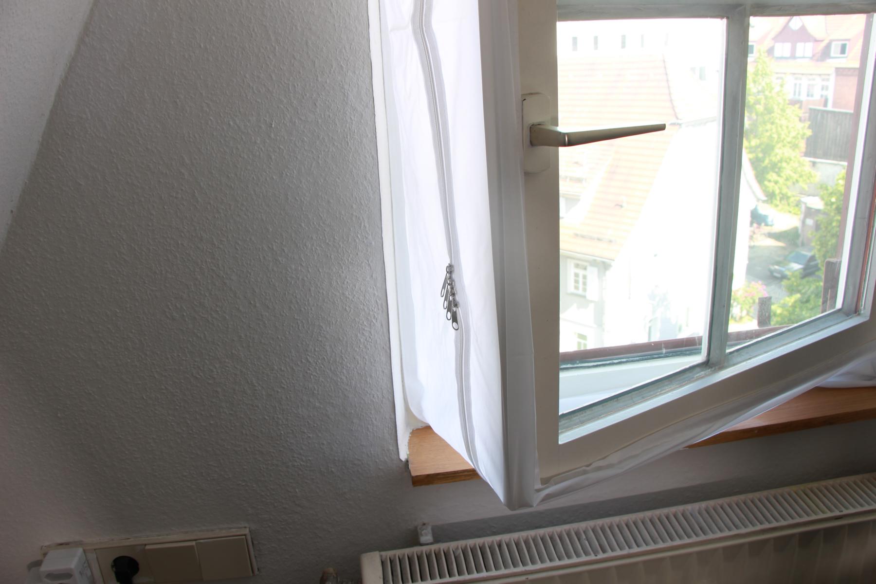 Die Fensterabdichtung ist am Fenster angebracht und man sieht, dass die Öffnung nicht zentral sondern etwas weiter rechts verläuft, weil eine Seite breiter und die andere kürzer ist.